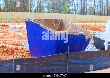 Der Müllcontainer befindet sich auf der Baustelle, umgeben von Schotter, der teilweise entfernt wird Stockfoto