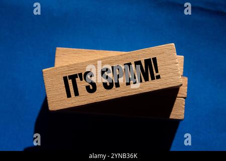 Es ist eine Spam-Nachricht auf Holzblöcken mit blauem Hintergrund. Konzeptionell ist das Spam-Symbol. Kopierbereich. Stockfoto