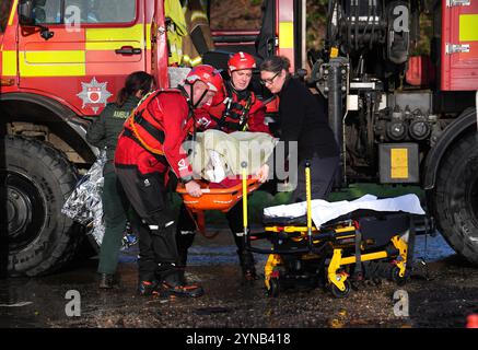 Eine in Decken gehüllte Einwohnerin wird betreut, als sie in ein Rettungsfahrzeug am Billing Aquadrome in Northamptonshire gebracht wird. Sturm Bert wird auch in Montag zu Störungen führen, nachdem sintflutartige Regengüsse am Wochenende „verheerende“ Überschwemmungen verursacht haben. Bilddatum: Montag, 25. November 2024. Stockfoto