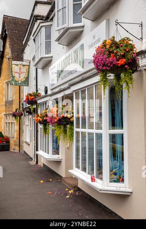 Großbritannien, England, Gloucestershire, Vale of Berkeley, Berkeley, Marktplatz, Blumenkörbe vor Geschäften und ehemaliger George Pub Stockfoto