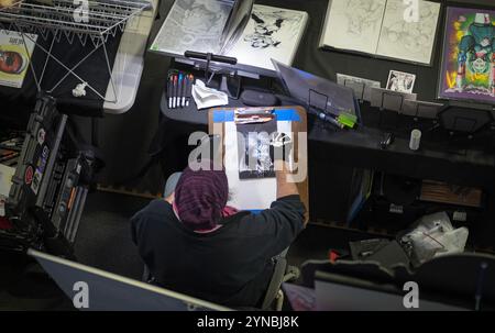 Ein Blick von oben auf einen anonymen Karikaturkünstler, der eine unheimliche, monströse Figur in Schwarzweiß zeichnet. Auf der Comic Con 2024 in Fishkill, New York Stockfoto