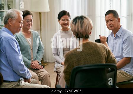 asiatische Beraterin, die eine Diskussionsrunde für eine Gruppe von Senioren leitet Stockfoto