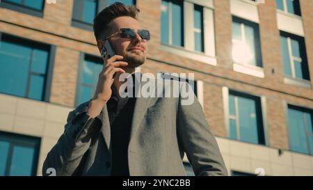 Selbstbewusster eleganter Mann in Sonnenbrille draußen in der Nähe des Bürogebäudes erfolgreicher reicher Geschäftsmann Unternehmer Unternehmensleiter Geschäftspartner Stockfoto