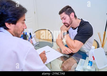 Ein Patient hört aufmerksam zu und berücksichtigt den ärztlichen Rat des Arztes während einer Konsultation und prüft ein Dokument in einer Klinik. Stockfoto