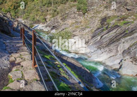 Halb ausgegrabener Pfad im Felsen mit der Fußgängerbrücke Los Pilones unten. Extremadura, Spanien Stockfoto