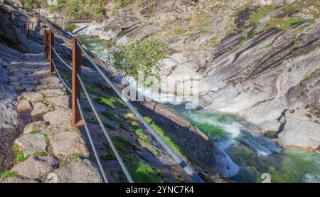 Halb ausgegrabener Pfad im Felsen mit der Fußgängerbrücke Los Pilones unten. Extremadura, Spanien Stockfoto