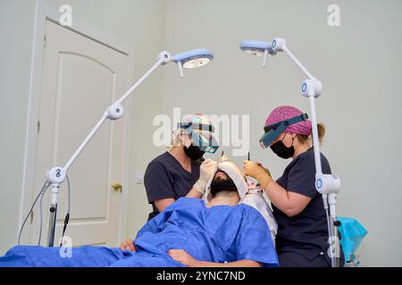 Haartransplantationschirurgie mit zwei Chirurgen und Patienten im OP Stockfoto