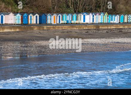 Eine Reihe von farbenfrohen oder bunt bemalten Strandhütten an der Küste der isle of wight uk, Strandhütten an der Küste der isle of wight in hellen Farben Stockfoto