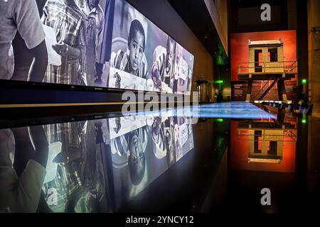 National Museum of African American History Greensboro Sit ins Washington DC | WASHINGTON D.C., Vereinigte Staaten — Ein reflektierender schwarzer Boden verdoppelt eine Wandlänge von Bildern aus der Zeit der Bürgerrechte, neben einer Nachbildung eines Wachturms der Staatsgefängnis Louisiana im National Museum of African American History and Culture. Der Wachturm Angolas, der 2013 vor Fertigstellung der Mauern in das Gebäude eingelassen wurde, verankert die Geschichtsgalerien des Museums, die die Segregation und ihre Vermächtnisse dokumentieren. Neben den Fotos erscheint ein „Black Power“-Schild. Stockfoto
