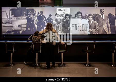National Museum of African American History Lunch Counter Exhibit Washington DC | WASHINGTON D.C., Vereinigte Staaten – Besucher sitzen an einer neu gestalteten Lunch Counter Exponate im National Museum of African American History and Culture, einer interaktiven Hommage an die Greensboro-Sit-ins von 1960. Vier Black College-Studenten inszenierten den ursprünglichen Protest an einem separaten Woolworth's Lunch Counter in Greensboro, North Carolina, um die breitere Sit-in-Bewegung gegen die Jim Crow-Segregation anzuzünden. Stockfoto