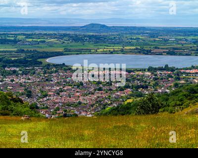 Blick auf die Stadt Cheddar von der Cheddar Gorge, eine Touristenattraktion in den Mendip Hills in Somerset im Südwesten Englands, Großbritannien, mit einem Reservoir in der Ferne. Stockfoto