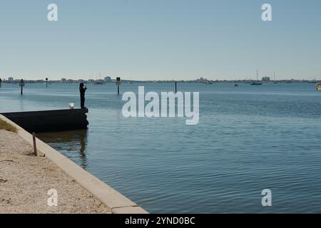 Führende Linie am Ufer des linken Mannes, der vor Gulfport, FL, angeln kann. Blick über das Outlet zur Boca Ciega Bay vom Yachthafen. Boote im Rücken ruhiges flaches Wasser. Sonnig Stockfoto