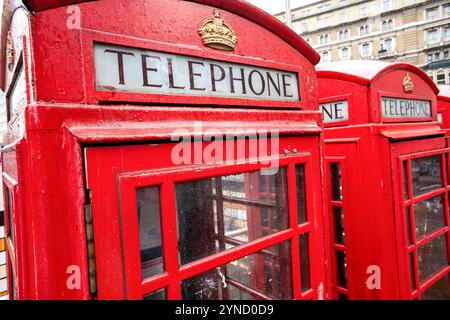 Rote Telefonzelle London | LONDON, Vereinigtes Königreich — Eine klassische rote Telefonzelle steht auf einer Londoner Straße, ein ikonisches Symbol britischen Erbes und urbanen Designs. Sir Giles Gilbert Scott entwarf den gusseisernen K6-Kiosk 1935, und diese markanten Kabinen mit ihrer leuchtend roten Farbe und dem Kronensymbol wurden im gesamten 20. Jahrhundert zum Inbegriff britischer Straßenlandschaften. Obwohl sie in der Ära der Mobiltelefone weitgehend überholt sind, wurden viele als geschützte Denkmäler erhalten oder für alternative Nutzungen im gesamten Vereinigten Königreich umgenutzt. Stockfoto
