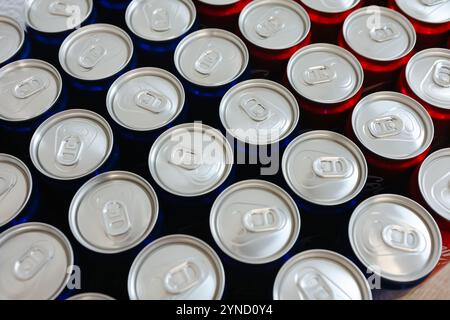 Blick von oben auf die ordentlich angeordneten roten und blauen Getränkedosen mit silbernen Platten, die Einfachheit, Erfrischung und modernes Design symbolisieren. Ideal für Themen Stockfoto