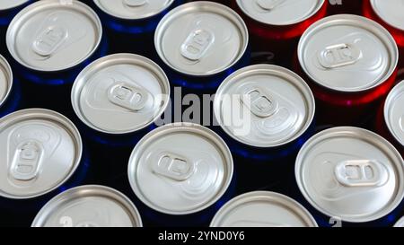 Blick von oben auf die ordentlich angeordneten roten und blauen Getränkedosen mit silbernen Platten, die Einfachheit, Erfrischung und modernes Design symbolisieren. Ideal für Themen Stockfoto