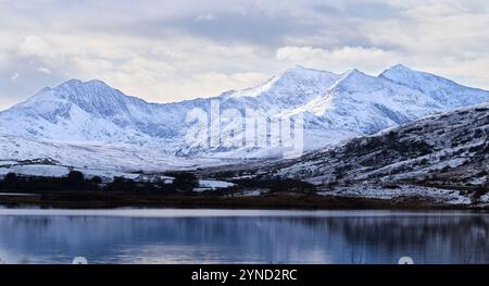 Gipfel des Mount Snowdon (Yr Wyddfa) über den Lake Llynnau Mymbyr, Snowdonia (Eryri), Wales, bedeckt mit Schnee an einem bewölkten Wintertag. Stockfoto