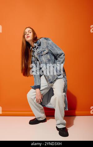 Ein junger Mann mit langen roten Haaren schlägt eine einzigartige Pose und drückt tiefe Emotionen aus. Stockfoto