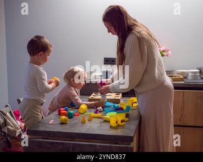 Mutter und zwei Kinder haben Spaß mit lehrreichen Spielzeugen in warmer und einladender Atmosphäre Stockfoto
