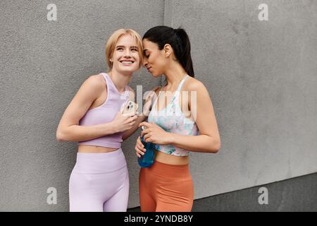 Zwei fröhliche junge Frauen verbringen nach einem Workout einen süßen Moment zusammen, um Liebe und Fitness zu genießen. Stockfoto