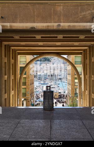 Marseille. Frankreich - 25. November 2024: Blick auf den Hafen von Marseille durch einen urbanen Bogen, der eine einzigartige Perspektive auf die pulsierende Uferpromenade der Stadt bietet Stockfoto