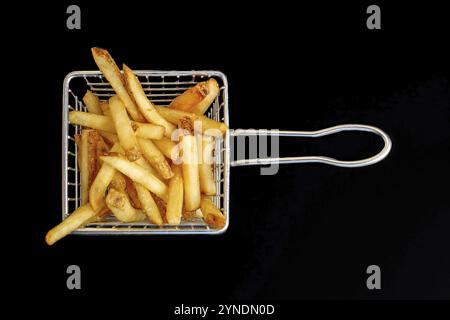 Aus der Vogelperspektive eines bescheidenen Korbs mit Pommes frites vor dunkler Kulisse Stockfoto