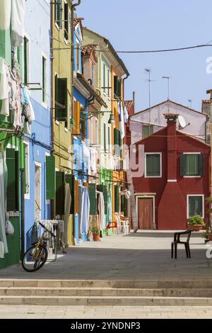 Idyllische Straße mit bunten Häusern und einem Fahrrad im sonnigen Licht und Wäscherei zum Trocknen, Burano, Venedig, Italien, Europa Stockfoto