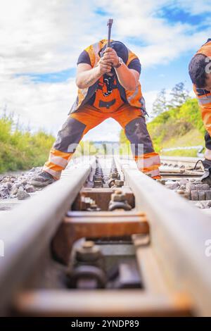 Zwei Bauarbeiter arbeiten auf den Schienen, schauen auf den Gleisen in ländlicher Umgebung, Schienenschweißen, Gleisbau Hermann Hessebahn, Calw, Stockfoto