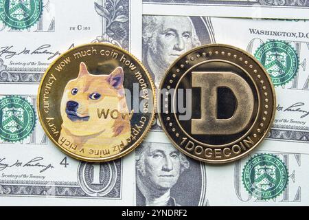 Calgary, Alberta, Kanada. Mai 2021. Ein paar Dogecoin mit ein-Dollar-Scheinen im Hintergrund Stockfoto