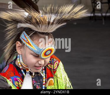 Calgary, Alberta, Kanada. Juni 2023. Eine mittelgroße Aufnahme eines Talents eines indigenen Kindes, das während der öffentlichen Veranstaltung gelbe traditionelle Tücher trägt Stockfoto