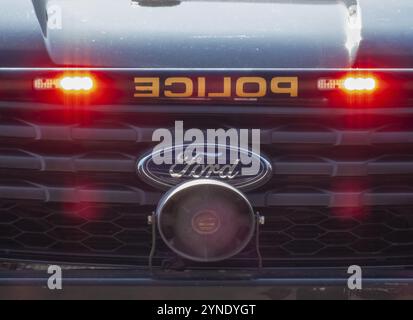Calgary, Alberta, Kanada. August 2024. Nahaufnahme des Frontgitters eines Polizeifahrzeugs mit dem Ford Emblem und blinkenden roten Lichtern, die das Gesetz symbolisieren Stockfoto