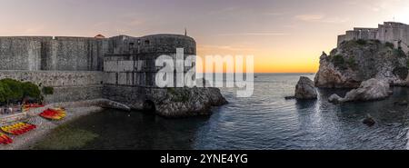 Foto panorámica con los tonos en el horizonte del atardecer, parte de la muralla y la fortaleza de Lovrijenac. Dubrovnik, Croacia Stockfoto