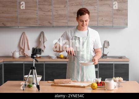 Männlicher Koch mit Teig und Obst, die Kochvideo in der Küche aufzeichnen Stockfoto