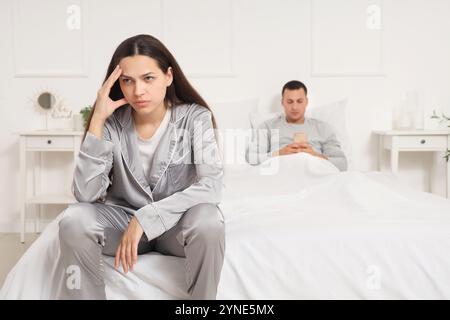 Beleidigte junge Frau, die nach einem Streit mit ihrem Mann im Schlafzimmer sitzt Stockfoto