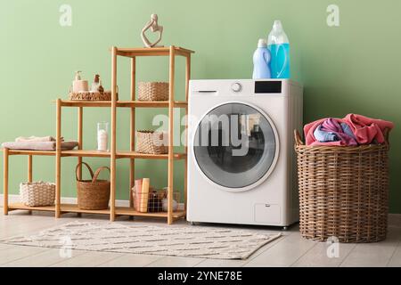 Moderne Waschmaschine, Regal und Korb mit Waschmaschine im Zimmer Stockfoto