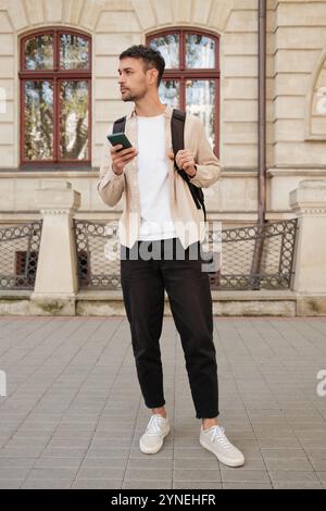 Selbstbewusster junger Mann, der die Stadt mit dem Smartphone in der Hand erkundet Stockfoto
