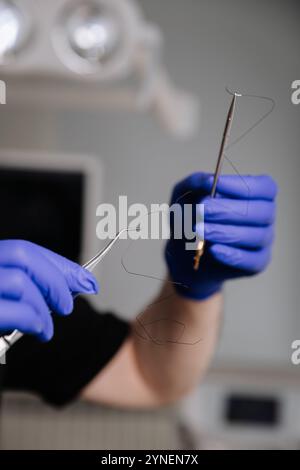 Zahnarzt, der Zahnseide hält und Werkzeuge zur Mundhygiene-Demonstration im klinischen Umfeld Stockfoto