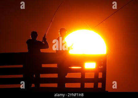 Isle Of Palms, Usa. November 2024. Fischer, die vom Sonnenaufgang umrahmt wurden, werfen ihre Linien am 25. November 2024 auf der Isle of Palms, South Carolina, ab. Quelle: Richard Ellis/Richard Ellis/Alamy Live News Stockfoto