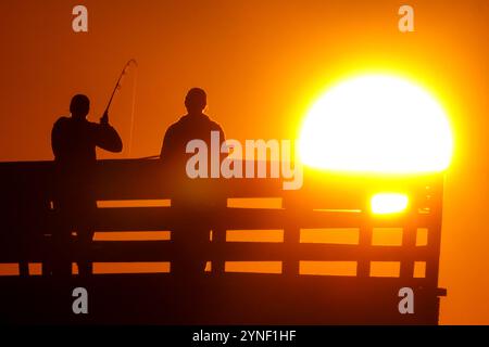 Isle Of Palms, Usa. November 2024. Fischer, die vom Sonnenaufgang umrahmt wurden, werfen ihre Linien am 25. November 2024 auf der Isle of Palms, South Carolina, ab. Quelle: Richard Ellis/Richard Ellis/Alamy Live News Stockfoto