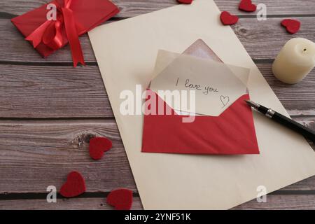 Romantischer Liebesbrief in rotem Umschlag auf rustikalem Holztisch Stockfoto