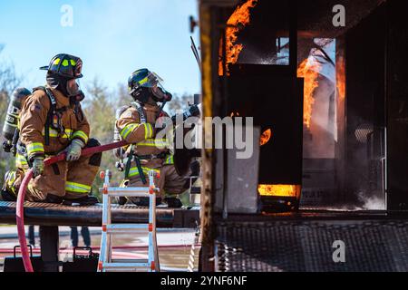 Die Feuerwehrleute der Joint Base San Antonio nehmen am 20. November 2024 an einer Live-Feuerübung in JBSA-Fort Sam Houston, Texas, Teil. Zweck der Schulung ist es, die Fähigkeit der Feuerwehr zu bewerten, einen Brand in einem Flugzeug zu löschen, während sie die Kontrolle über die Situation behält und ein Team leitet. Dies bereitet sie auf Notfälle in der Praxis vor. Während des Trainings wechselten die Mitglieder die Positionen im Trupp, um sicherzustellen, dass alle mit jeder Aufgabe vertraut waren. (Foto der U.S. Air Force von Taylor Curry) Stockfoto