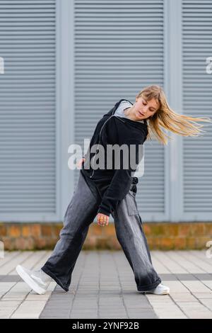 Tänzer, der tagsüber dynamische Bewegungen auf dem städtischen Straßenbelag spielt Stockfoto