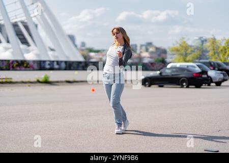 Die junge Frau tanzt fröhlich auf einem sonnigen Parkplatz im Freien Stockfoto