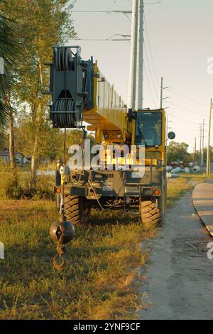 Wide Front View-KRAN für RAUES GELÄNDE mit hängendem Krankugelhaken, schwarze Reifen-gelbe Felgen. Baukranfahrzeug auf einer Baustelle. Auf der Seite des Temp Stockfoto