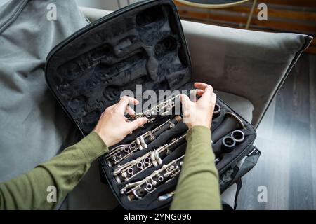 Man Hands legt zerlegte schwarze Klarinette in einen speziellen Fall, inspiziert Teile der Flöte nach dem Spielen Stockfoto