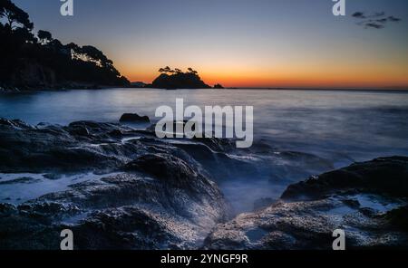 Sonnenaufgang am Strand von Belladona mit Cap Roig cape im Hintergrund an der Costa Brava (Calonge, Girona, Katalonien, Spanien) ESP: Amanecer en la playa Stockfoto