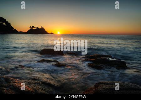 Sonnenaufgang am Strand von Belladona mit Cap Roig cape im Hintergrund an der Costa Brava (Calonge, Girona, Katalonien, Spanien) ESP: Amanecer en la playa Stockfoto