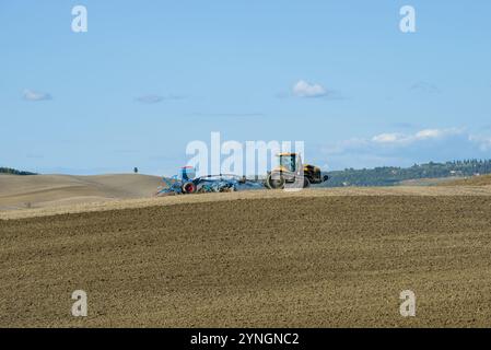 TOSKANA, ITALIEN - 21. SEPTEMBER 2017: Raupenschlepper mit Pflanzmaschine arbeitet im Bereich des Sonnentages September Stockfoto