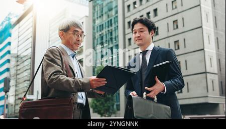 Outdoor-, Teamwork- und Geschäftsleute in der Stadt für Dokumente, Entwicklung oder Reden. Stadtplaner, Übergabe und erfahrene professionelle Japaner Stockfoto