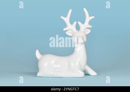 Weiße keramische Weihnachts- oder Winterdekoration Hirschfigur auf hellblauem Hintergrund Stockfoto