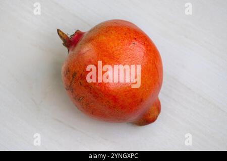 Ein reifer Granatapfel (Punica granatum) auf hellem hölzernem Hintergrund. Draufsicht. Stockfoto